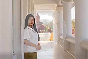 Beautiful thai woman in a white traditional thai dress is standing in white temple with smilingly face photo
