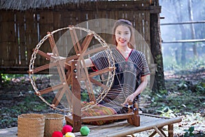 Beautiful Thai women smile in karen suit spinning thread on a ba