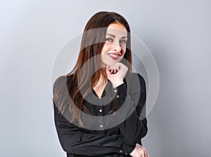 Beautiful thinking happy smiling business woman with toothy smile in black shirt on grey blue background with empty copy space.