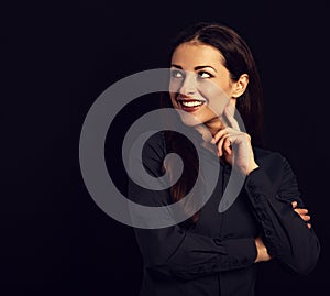 Beautiful thinking toothy laughing business woman with folded arms in blue shirt on black background with empty copy space.
