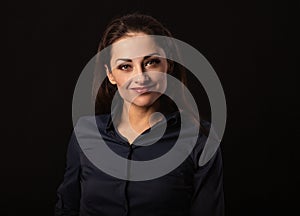 Beautiful thinking toothy laughing business woman with folded arms in blue shirt on black background with empty copy space.