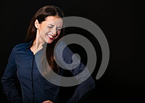 Beautiful thinking toothy laughing business woman with folded arms in blue shirt on black background with empty copy space for