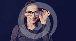 Beautiful thinking toothy smiling business woman in blue shirt on black background with empty copy space for text. Closeup