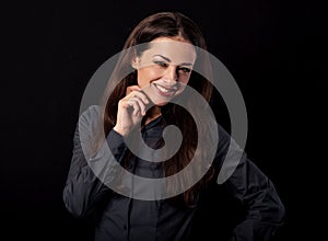 Beautiful thinking toothy smiling business woman with folded arms in blue shirt on black background with empty copy space for text