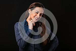 Beautiful thinking toothy smiling business woman with folded arms in blue shirt on black background with empty copy space for text