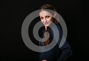 Beautiful thinking toothy smiling business woman with folded arms in blue shirt on black background with empty copy space for text