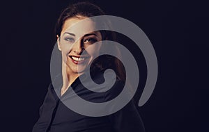 Beautiful thinking toothy smiling business woman looking in blue shirt on black background with empty copy space for text. Closeup