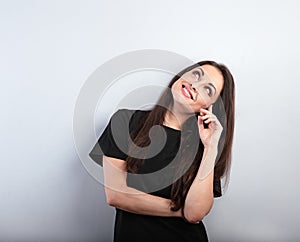 Beautiful thinking woman with natural makeup  looking up with hand under the face in casual black t-shirt on light blue background