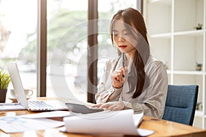 A beautiful and thoughtful Asian businesswoman is focusing on her work at her desk