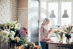 Beautiful thoughtful businesswoman florist with coffee cup sitting in office