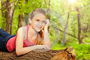 Beautiful thoughtful girl laying on the log