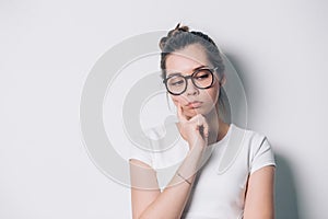 Beautiful thoughtful woman with glasses on a white background. Expressive facial features.