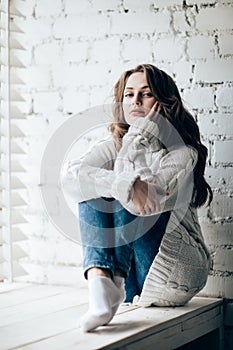 Beautiful thoughtful woman relaxing on brick wall background