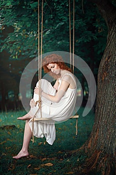 Beautiful thoughtful woman on a swing