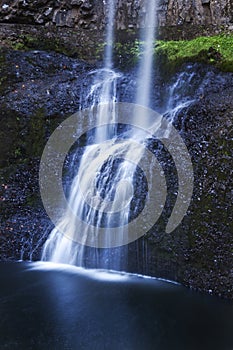 Beautiful tiered waterfall cascading over rocks with a soft ethereal blue tone refection in water