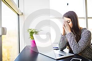 Beautiful tired business woman is holding massaging her nose bridge while working in office