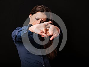 Beautiful tired business woman relaxing and doing stretching exercise on neck and shoulder blades pulling the parms in blue shirt