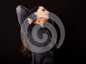 Beautiful tired business woman relaxing and stretching exercise on neck and shoulders in blue shirt isolated on black background