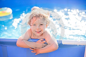 Beautiful toddler child, blond boy, swimming in a pool in backyard