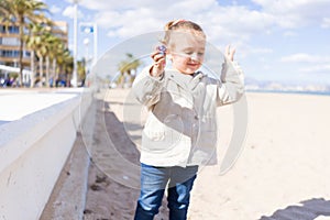Beautiful toddler child girl wearing jacket playing with the sand on the beach