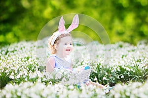 Beautiful toddler girl Easter eggs in first spring flowers