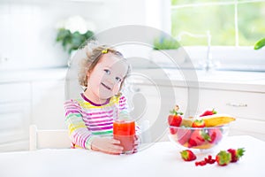 Beautiful toddler girl having breakfast drinking juice