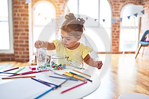 Beautiful toddler standing playing with chocolate colored balls on the table at kindergarten