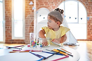 Beautiful toddler standing playing with chocolate colored balls on the table at kindergarten