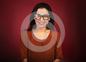 Beautiful toothy laughing woman  looking happy in eye glasses in casual orange t-shirt on red background with empty copy space.