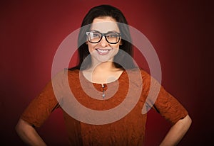 Beautiful toothy smiling happy business woman with red lipstick looking happy in eye glasses in casual black polluver  on dark red