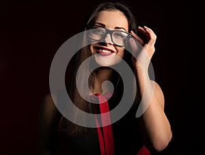 Beautiful toothy smiling happy business woman with red lipstick looking happy in eye glasses in fashion red dress on dark red