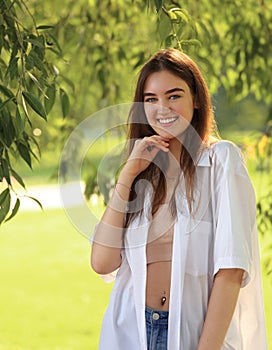 Beautiful toothy smiling teen woman looking happy outdoors summer green trees background. Closeup portrait