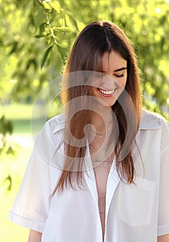 Beautiful toothy smiling teen woman looking happy outdoors summer green trees background. Closeup portrait