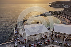 Beautiful top view of bustling waterfront restaurant filled with patrons on gorgeous sunset background. RIU hotel, Gran Canaria.