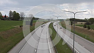 Beautiful top view of E4 highway with several cars. Green side fields and stormy sky background.