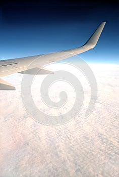 Beautiful top view from passenger supersonic airplane window flying high above white clouds in the sky