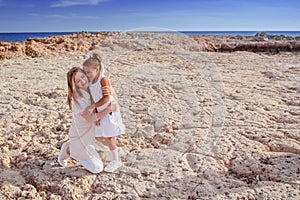 Beautiful top view of young mother playing with daughter with white hat at the sea background. Family vacation. Travel. Female