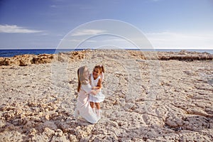 Beautiful top view of young mother playing with daughter with white hat at the sea background. Family vacation. Travel. Female