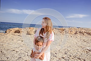 Beautiful top view of young mother playing with daughter with white hat at the sea background. Family vacation. Travel. Female