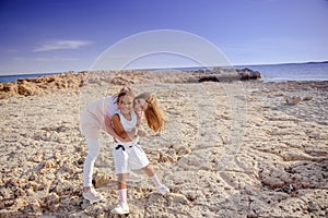 Beautiful top view of young mother playing with daughter with white hat at the sea background. Family vacation. Travel. Female