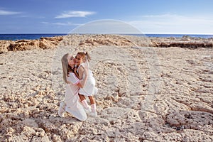 Beautiful top view of young mother playing with daughter with white hat at the sea background. Family vacation. Travel. Female