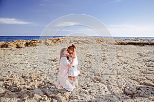 Beautiful top view of young mother playing with daughter with white hat at the sea background. Family vacation. Travel. Female