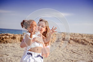 Beautiful top view of young mother playing with daughter with white hat at the sea background. Family vacation. Travel. Female