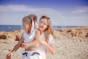 Beautiful top view of young mother playing with daughter with white hat at the sea background. Family vacation. Travel. Female