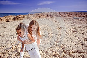 Beautiful top view of young mother playing with daughter with white hat at the sea background. Family vacation. Travel. Female