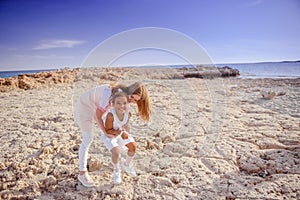 Beautiful top view of young mother playing with daughter with white hat at the sea background. Family vacation. Travel. Female