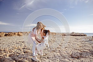 Beautiful top view of young mother playing with daughter with white hat at the sea background. Family vacation. Travel. Female