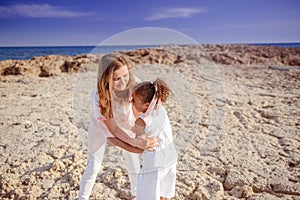 Beautiful top view of young mother playing with daughter with white hat at the sea background. Family vacation. Travel. Female