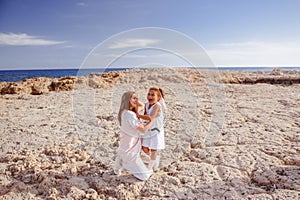 Beautiful top view of young mother playing with daughter with white hat at the sea background. Family vacation. Travel. Female