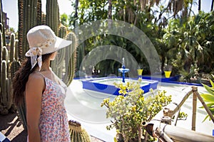 Beautiful tourist enjoying the fountain and pond of the Majorelle garden in Marrakech (Morocco).